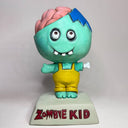 Toy figure of a cartoon zombie child with a brain on top, wearing yellow overalls, on a white background.