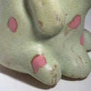 Close-up of a ceramic figure with pink spots on a white background