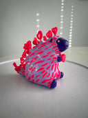 Colorful plastic toy resembling a hedgehog on a white surface with a light gray background