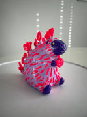 Colorful plastic toy resembling a hedgehog on a white surface with a light gray background