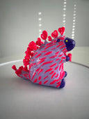 Colorful plastic toy resembling a hedgehog on a white surface with a light gray background