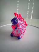 Colorful plastic toy resembling a hedgehog on a white surface with a light gray background
