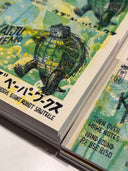 Stack of memo pads with bright colorful covers and an ink illustration of a roaring kaiju that says "kaiju memo"