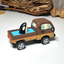 Painted small whittled wooden sculpture of a brown striped pick up truck, with the pick up filled with water. The head of a killer whale peeks out from the water.