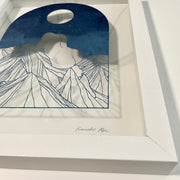  Delicate paper cutting made out of blue dyed paper of a woman's nude body sitting atop of a mountain range. She has no head and is turned away so only her back and butt are showing. A full moon is in the night sky.