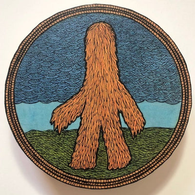 Round panel with a strongly outlined ink drawing of a tall figure walking on 2 legs with its body completely covered in brown fur, hiding even its face. It stands on green ground with a cloudy overcast sky behind.