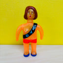 Sparkly orange vinyl figure of a topless woman wearing a sash.