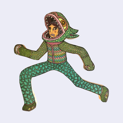 Die cut wooden sculpture of a person wearing a monster costume, with the hood down to reveal their real face. It is mid run. 