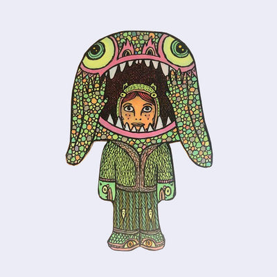 Die cut wooden sculpture of a small person wearing a large monster costume, wearing an all knit clothing.