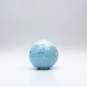 Small glossy blue ceramic sculpture of a round character with tiny legs and a closed eye gleeful expression. The top of its head is white like a snow capped mountain.