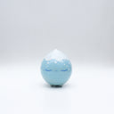 Small glossy blue ceramic sculpture of a round character with tiny legs and a closed eye, slightly pouty expression. The top of its head is white like a snow capped mountain.