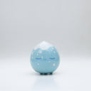 Small glossy blue ceramic sculpture of a round character with tiny legs and a closed eye, sleepy expression. The top of its head is white like a snow capped mountain.