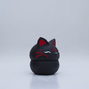 Black clay pot with a lid that looks like a fox's head, a matching black color with red ears and face paint. It has closed eyes and a small white nose. The bowl has no body details.