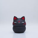 Black clay pot with a lid that looks like a fox's head, a matching black color with red ears and face paint. It has closed eyes and a small white nose. The bowl has no body details.