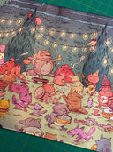 Neoprene desk mat with a colorful illustration of fantasy characters having an outdoor party with food and music, under string lights.