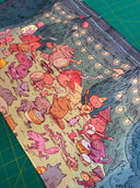 Neoprene desk mat with a colorful illustration of fantasy characters having an outdoor party with food and music, under string lights.