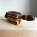 Whittled wooden sculpture of a cat shaped like a bus from My Neighbor Totoro. Its tail sticks straight out and it has a smiling face.