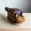 Whittled wooden sculpture of a cat shaped like a bus from My Neighbor Totoro. Its tail sticks straight out and it has a smiling face.