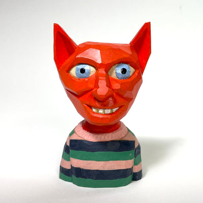 Painted whittled wood sculpture of the bust of a red devil, with pointed ears and big blue eyes. It wears a striped sweater: blue, green and a muted pink.