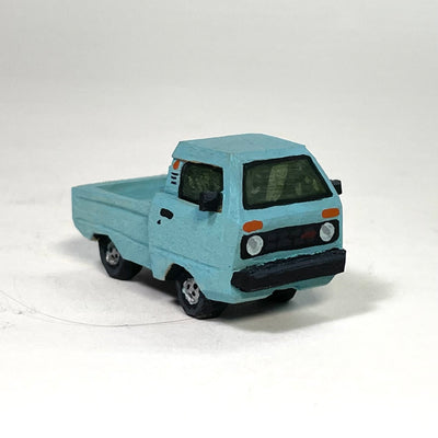 Painted whittled wood sculpture of a blue old school pickup truck, with a large cab and small truck bed. 