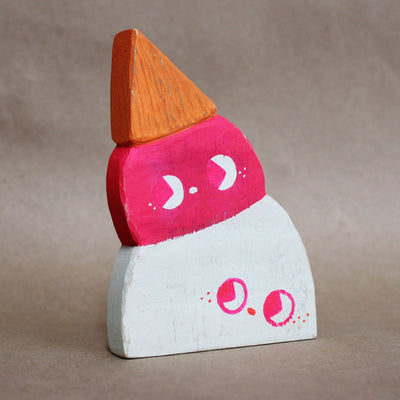 Die cut painted wooden sculpture of an upside down double scoop ice cream cone. One scoop is pink and the other is white, they both have cute drawn on faces looking off to the side.