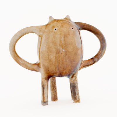 Ceramic sculpture of a brown character with small ears and eyes and standing on four thin legs. It has mug handle like shapes coming out of its sides.