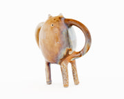 Ceramic sculpture of a brown character with small ears and eyes and standing on four thin legs. It has mug handle like shapes coming out of its sides.