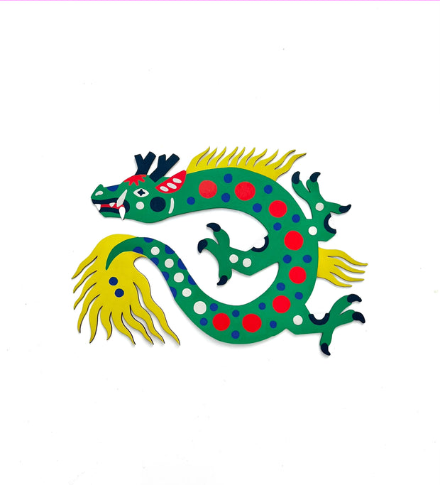 Die cut, brightly painted wooden sculpture of a folk art style dragon, green with red, blue and white polka dots. It has a wild yellow mane and tail.