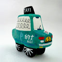 Clay sculpture of a cartoon style taxi, green in coloring with a cute smiley face.