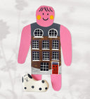 Paper cut out of a person wearing a shirt that resembles a building. Sitting at her feet is a black and white dog.