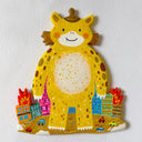 Flat colorful sculpture of a kaiju monster, a cute yellow character with spots standing in a lot around burning colorful buildings.