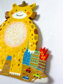 Flat colorful sculpture of a kaiju monster, a cute yellow character with spots standing in a lot around burning colorful buildings.