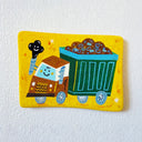 A flat artwork with rounded corners featuring a colorful, whimsical illustration of a dump truck on a bright yellow background, mounted on a textured white wall.