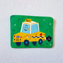 A flat artwork featuring a smiling yellow taxi on a green background, mounted on a white textured wall.