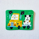A flat artwork featuring a colorful cartoon illustration of a yellow truck carrying a Dalmatian dog, set against a white textured wall.