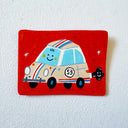A square hand-painted flat artwork featuring a whimsical cartoon race car on a bright red background, mounted on a textured white wall.