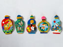 Five colorful hand-painted flat clay miniature bottles with animal and nature motifs, displayed side-by-side on a white textured wall.