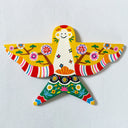 A colorful hand-painted wooden bird wall hanging with floral patterns and striped wings, mounted on a textured white wall.