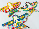 Three colorful hand-painted wooden bird ornaments with traditional folk art patterns, displayed on a white textured background.