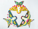A colorful decorative wall hanging made of three stylized bird shapes arranged in a circle, each filled with intricate floral and geometric folk-art patterns in yellow, blue, green, red, pink, black, and white, photographed against a plain light background.