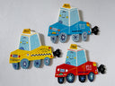 3 flat sculptures of cartoon style taxis with cute smiley faces and a cartoon plume of exhaust smoke coming out the tailpipe.