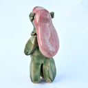 Ceramic sculpture of a green fish creature - Japanese yokai Amabie - standing on thick legs with her arms at her side. She has long pink hair and a bird/turtle beak.  Backside.
