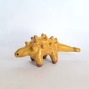 Yellow ceramic dinosaur figurine on a white background
