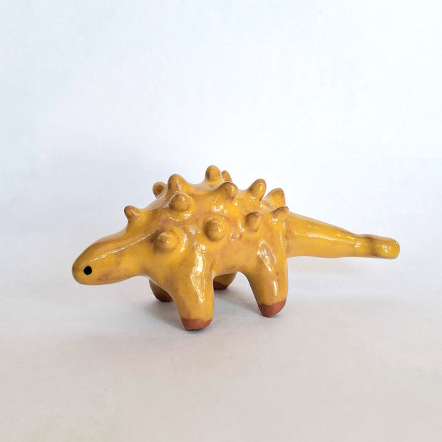 Yellow ceramic dinosaur figurine on a white background