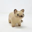 Ceramic sculpture of a tan cat with dark brown ears, paws, tail and snout. It stands with black eyes and a simply drawn nose and whiskers. It has 2 tails.