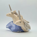 Ceramic sculpture of 2 unicorn busts, white and speckled. They emerge from a wave shape base.