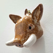 Ceramic sculpture of a boar head, with brown specked coloring and thick white tusks.