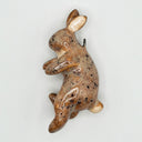 Brown spotted ceramic sculpture of a rabbit with a clip for hanging out the back.