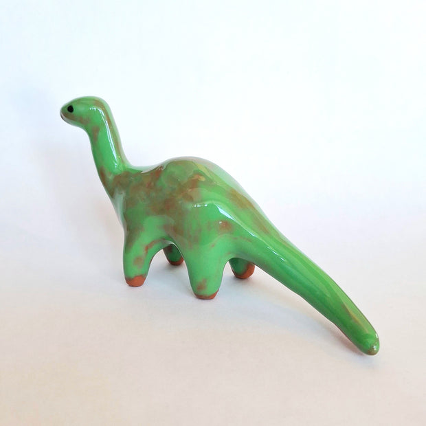 Green ceramic dinosaur figurine on a white background