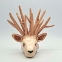 Ceramic sculpture of a deer head with many, many antlers and a red eye. 